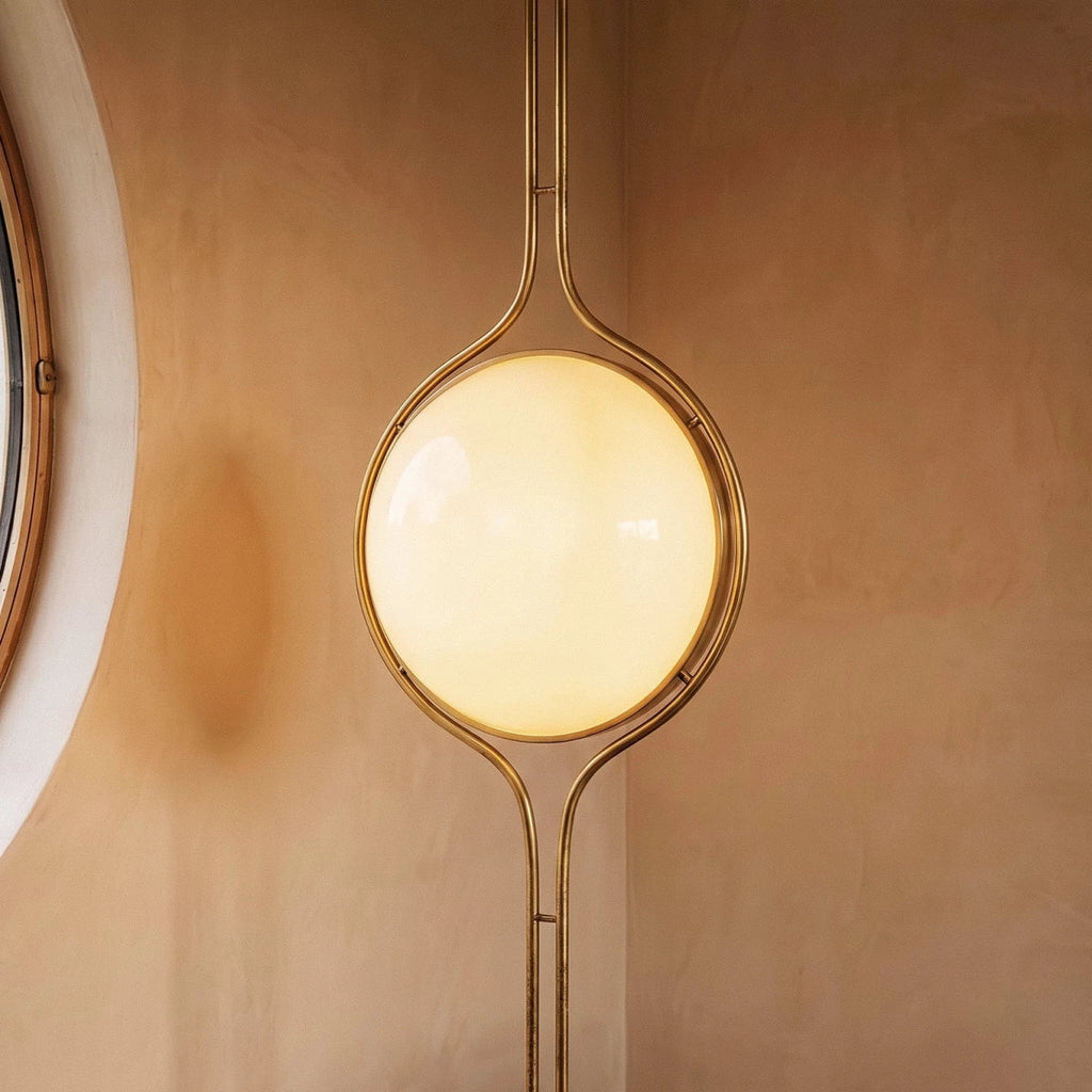 Clérachic floor-to-ceiling lamp in brass, set into a terracotta-plastered corner where the lit globe casts a soft pool of light on the wall.