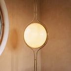 Clérachic floor-to-ceiling lamp in brass, set into a terracotta-plastered corner where the lit globe casts a soft pool of light on the wall.