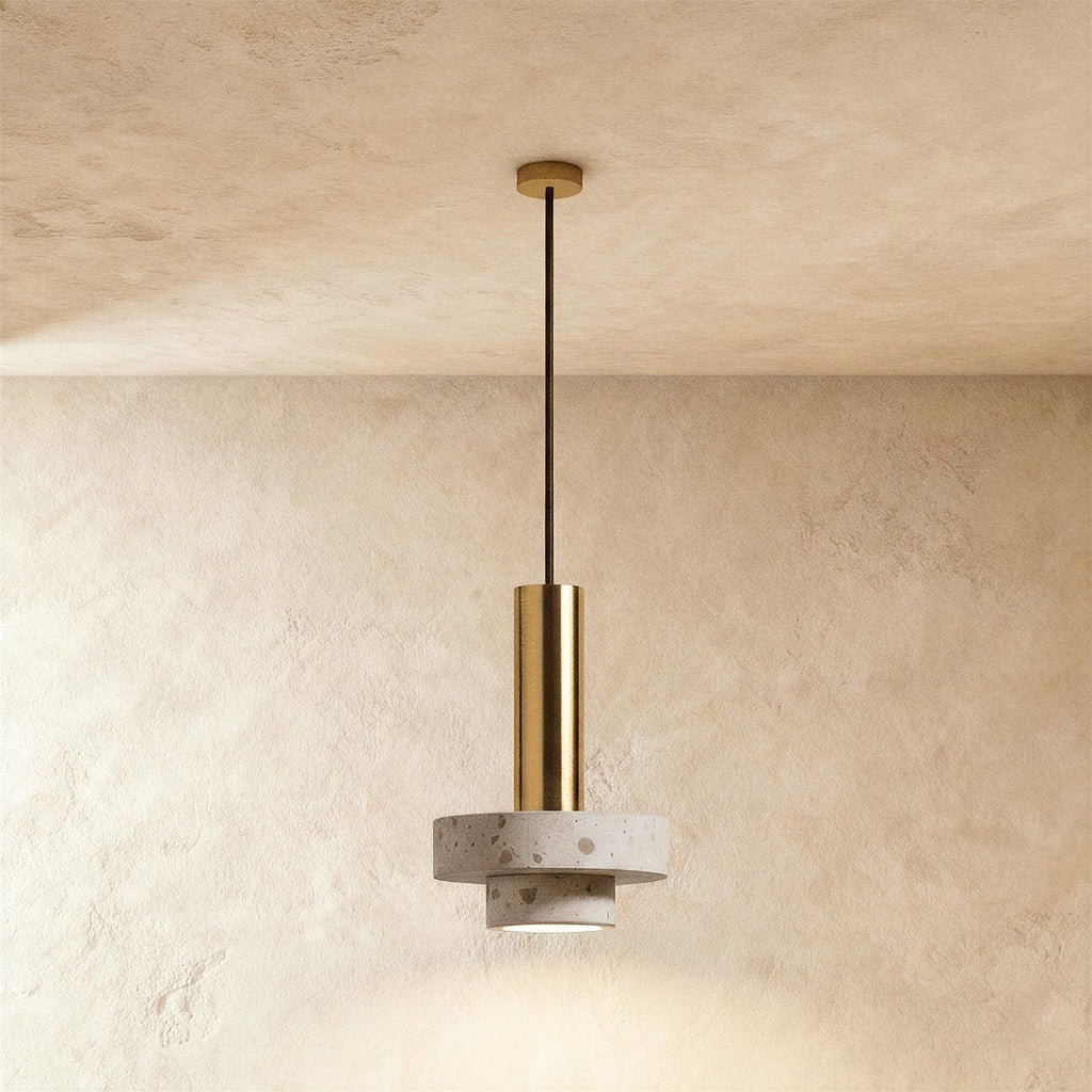 Clérachic compact pendant with a gold-toned cylinder above two stacked pale terrazzo discs, hung on a gold-toned rod from the ceiling.