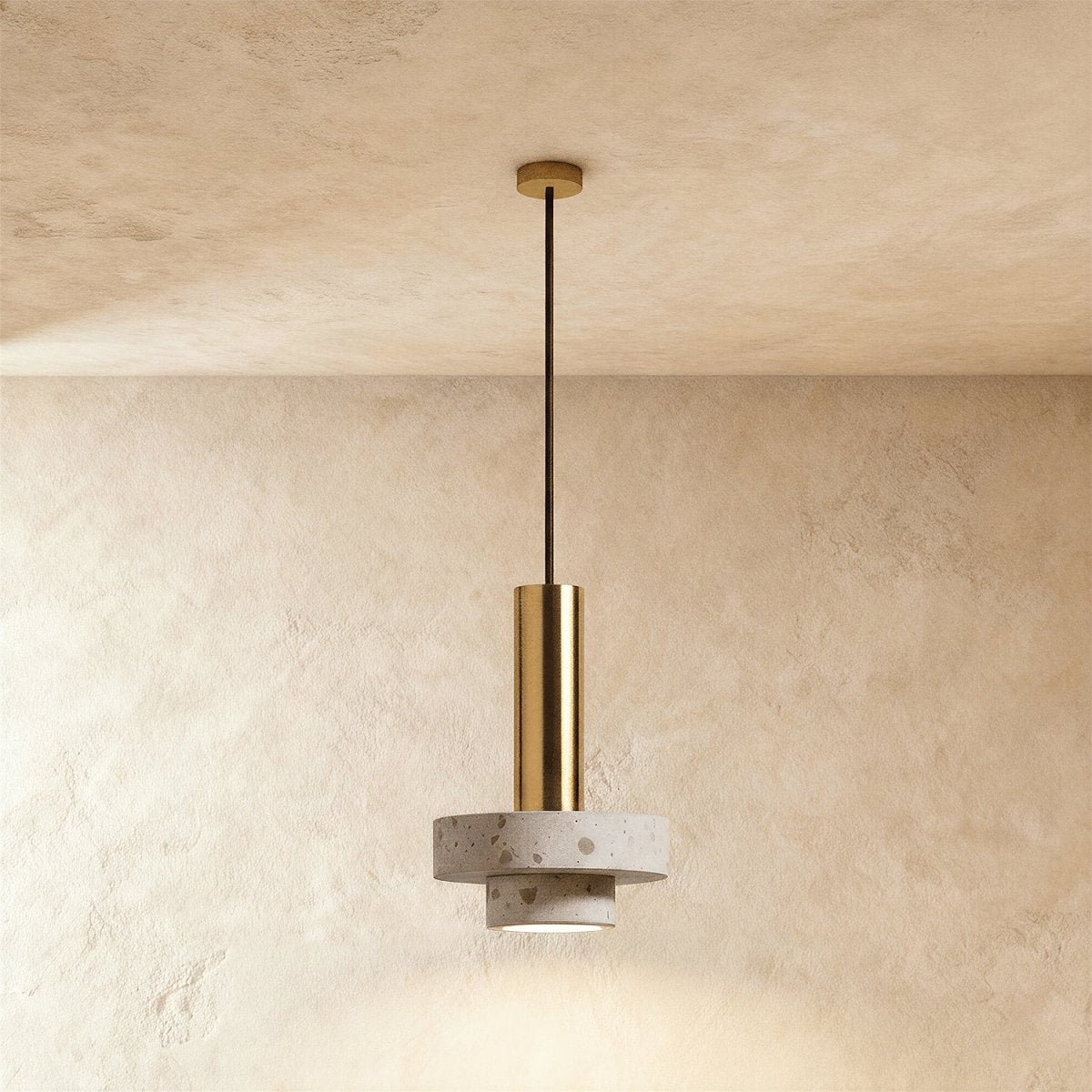 Clérachic compact pendant with a gold-toned cylinder above two stacked pale terrazzo discs, hung on a gold-toned rod from the ceiling.
