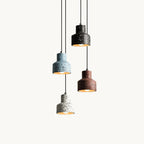 Four small terrazzo pendants from Clérachic hang at different heights on a plain white backdrop, in blue, black, deep red and white.