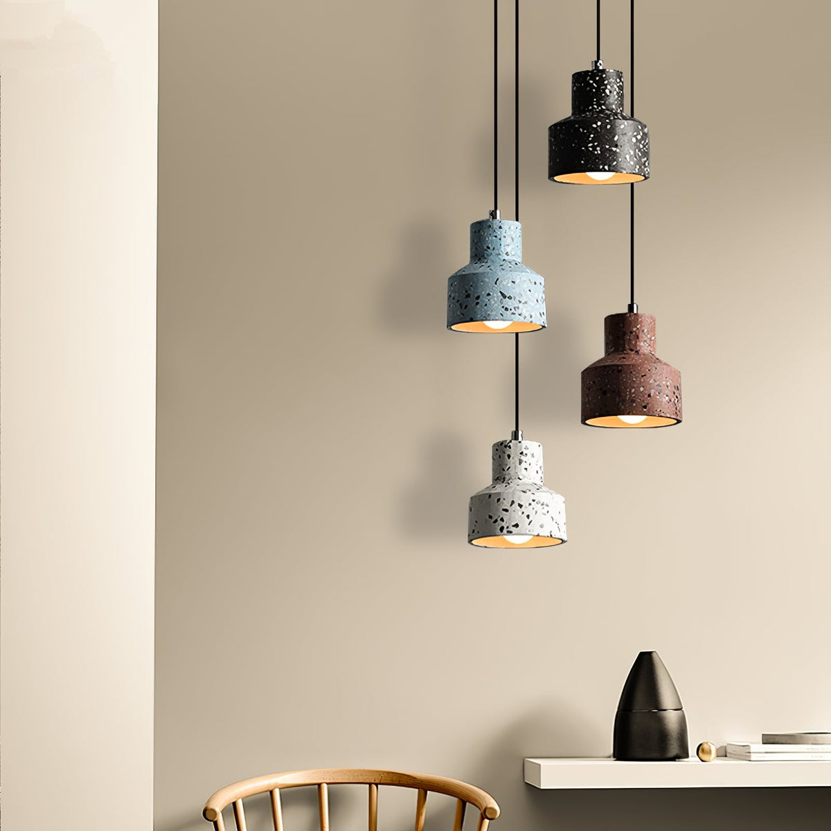 Another view of this Clérachic pendant group beside a sand wall and a shelf, blue, black, red and white shades hanging at staggered heights.