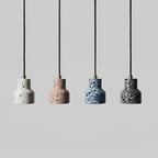 Four Clérachic terrazzo pendants in a line on black cords with brass fittings, in white, rose, blue and charcoal speckle.