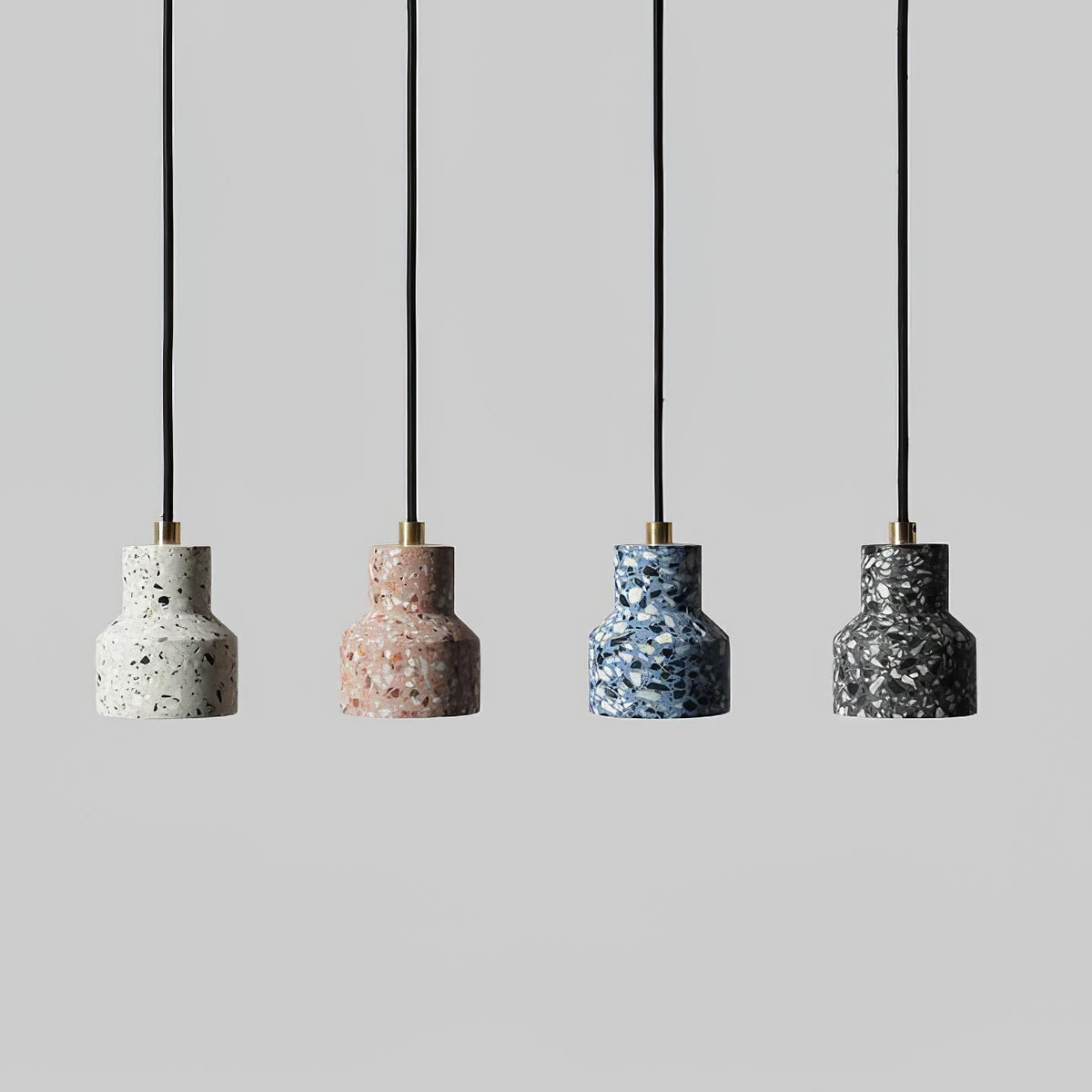 Four Clérachic terrazzo pendants in a line on black cords with brass fittings, in white, rose, blue and charcoal speckle.