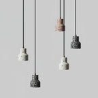Five of these Clérachic pendants hang at staggered heights on black cords, their speckled shades in white, rose and charcoal.
