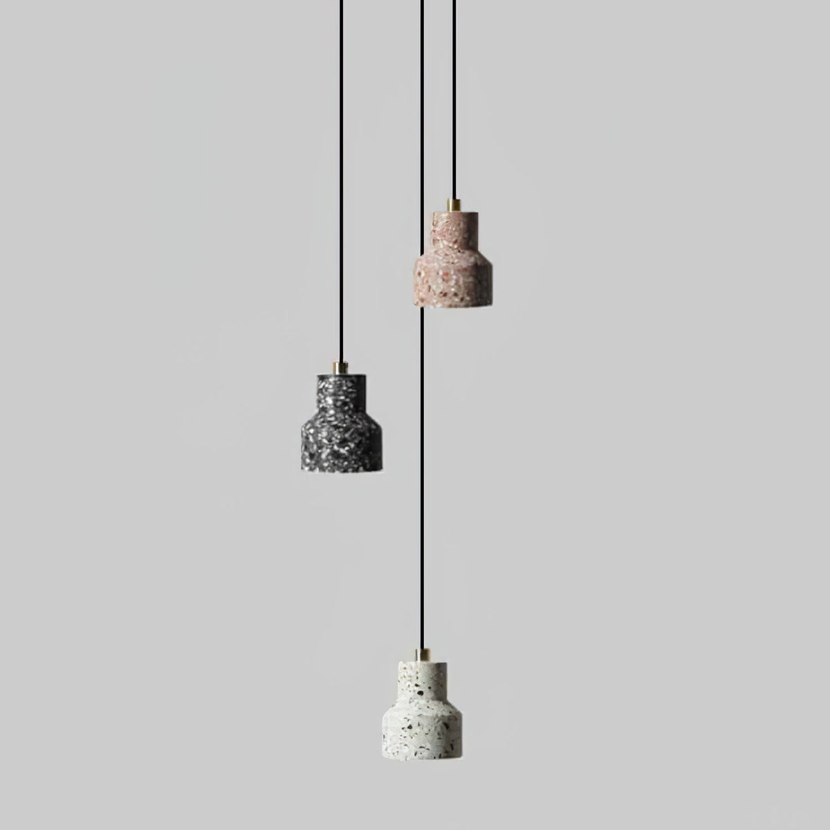 Three Clérachic terrazzo shades in charcoal, rose and white hang at different heights on thin black cords against light grey.