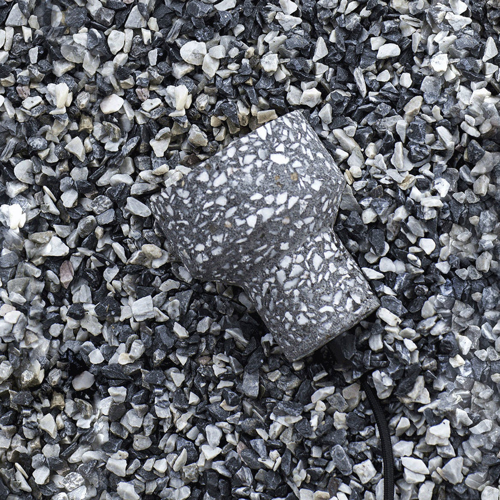 A charcoal terrazzo shade from Clérachic lies on grey and white gravel, showing the chunky stone chips set into the cement.
