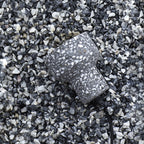 A charcoal terrazzo shade from Clérachic lies on grey and white gravel, showing the chunky stone chips set into the cement.