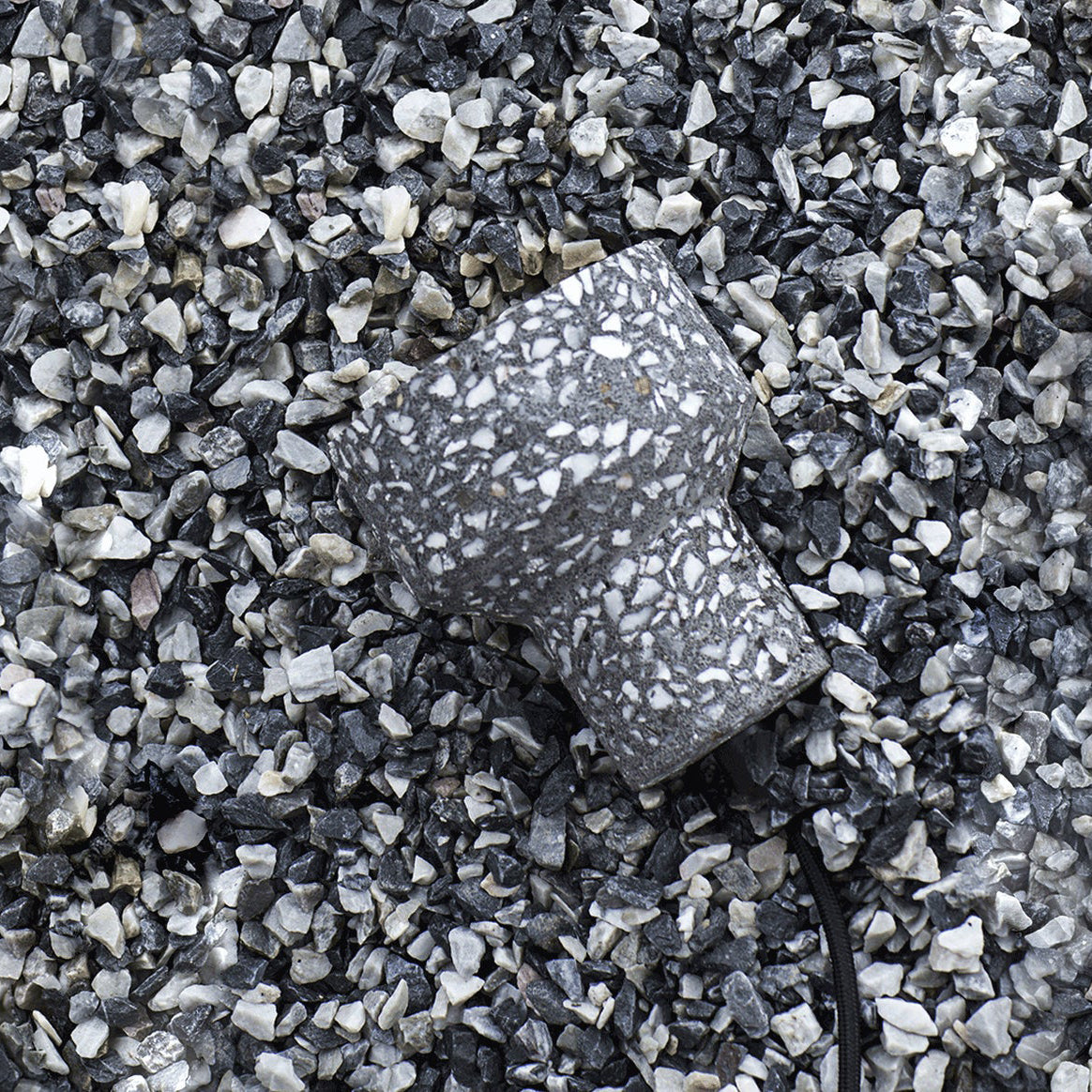 A charcoal terrazzo shade from Clérachic lies on grey and white gravel, showing the chunky stone chips set into the cement.