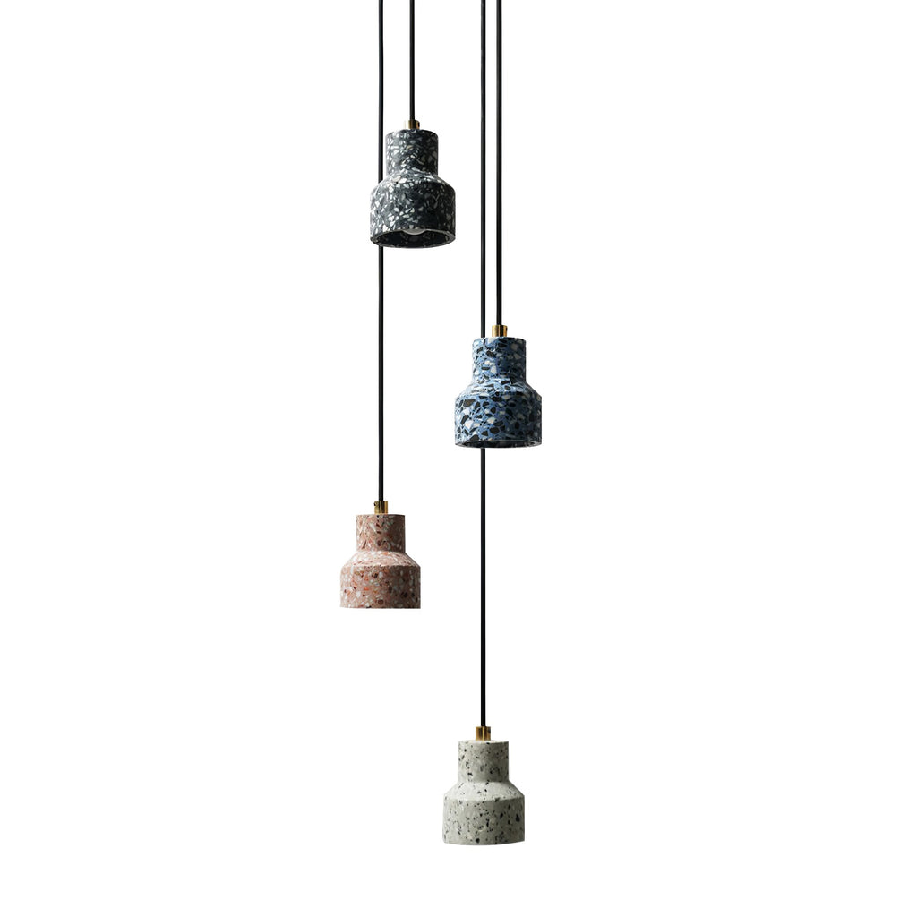 Four Clérachic terrazzo pendants on a white backdrop, hanging on black cords at staggered heights in black, blue, rose and grey.