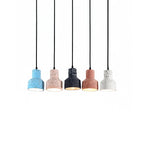 Five Clérachic cement pendants hang in a line on a white backdrop, the blue, pink, black, salmon and white shades lit from inside.