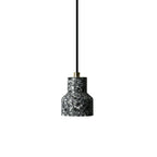 A single charcoal terrazzo pendant from Clérachic with a brass cord fitting hangs on a black cord against white.