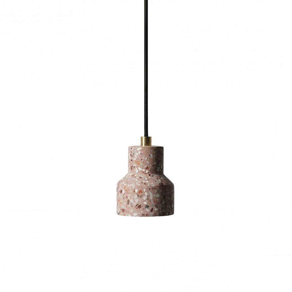 A single rose terrazzo pendant from Clérachic with a brass fitting hangs on a black cord, its shade flecked with small stone chips.