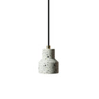 A single white terrazzo pendant from Clérachic hangs on a black cord with a brass fitting, its shade flecked with grey and black chips.