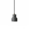A single charcoal terrazzo pendant from Clérachic hangs on a black cord with a brass fitting, its shade flecked with white chips.