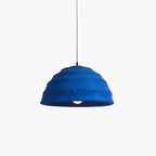 Studio view of the Clérachic Textured Blue Dome Pendant Light, its ridged cobalt shade lit from within and hung on a slim black cord.