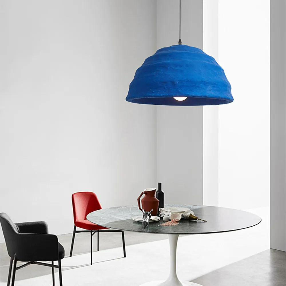 The Clérachic Textured Blue Dome Pendant Light hung low over a round marble dining table set with red and black chairs.