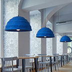 Three Clérachic Textured Blue Dome Pendant Lights in a row above the long tables of a tiled café dining hall.