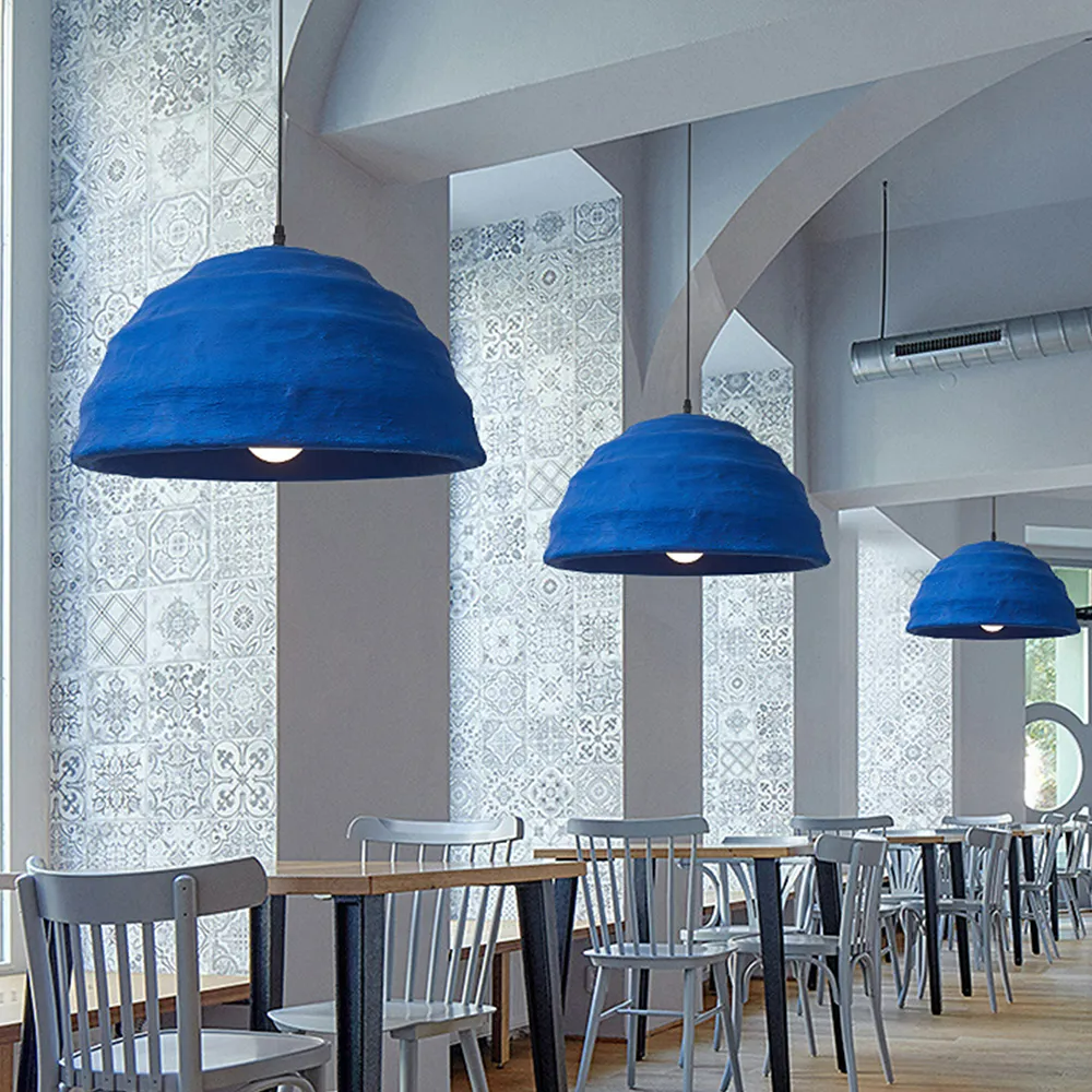 Three Clérachic Textured Blue Dome Pendant Lights in a row above the long tables of a tiled café dining hall.