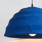 Close-up of the Clérachic Textured Blue Dome Pendant Light's torn lower rim and the round bulb glowing inside the shade.