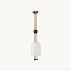 A Clérachic ribbed white cylinder pendant on a plain white backdrop, hung from a brass canopy on three brass rods with a black ball partway down.