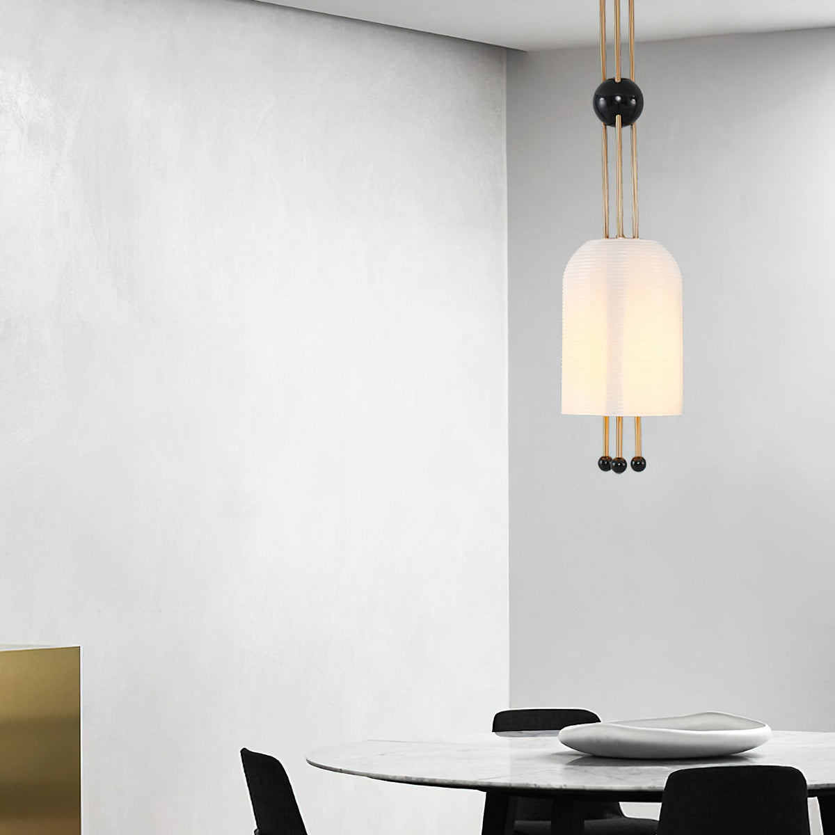 A single Clérachic white pendant hung against a grey plaster wall, with a round table and black chairs below at the bottom of the frame.
