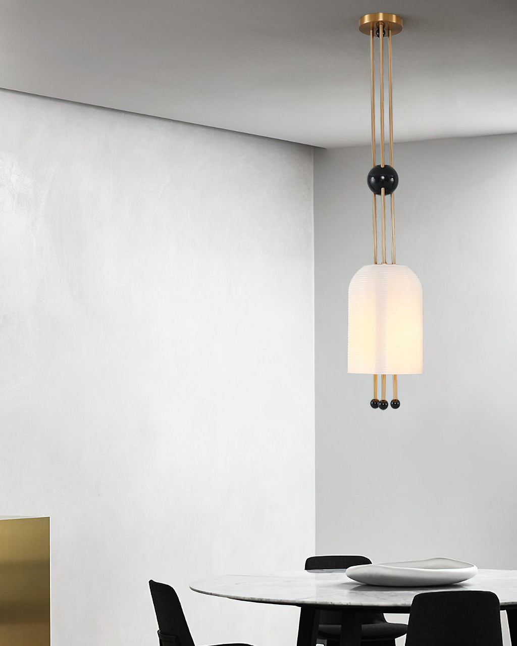 A Clérachic white pendant hung against a grey plaster wall, with a round white table and black chairs below.
