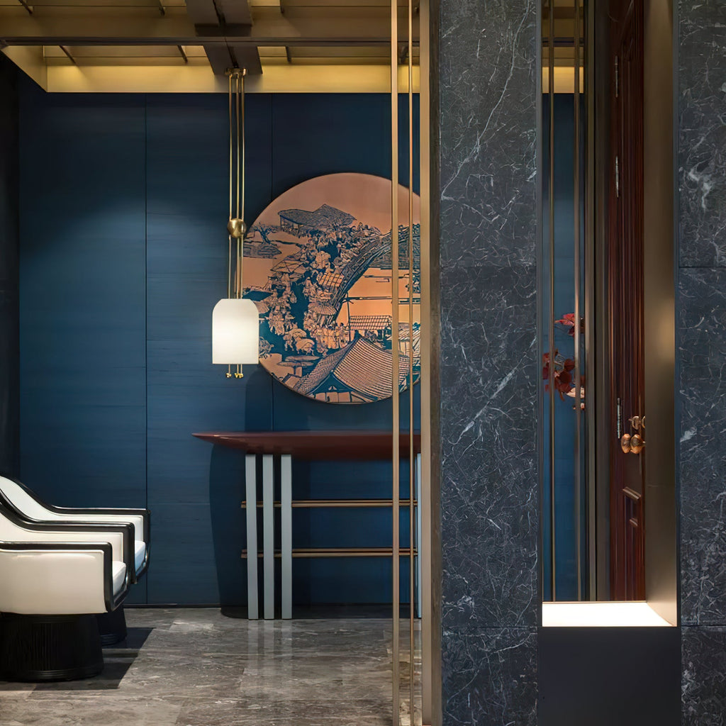 A Clérachic pendant in front of a round blue-and-copper artwork on a deep blue wall, above a red-topped console table.