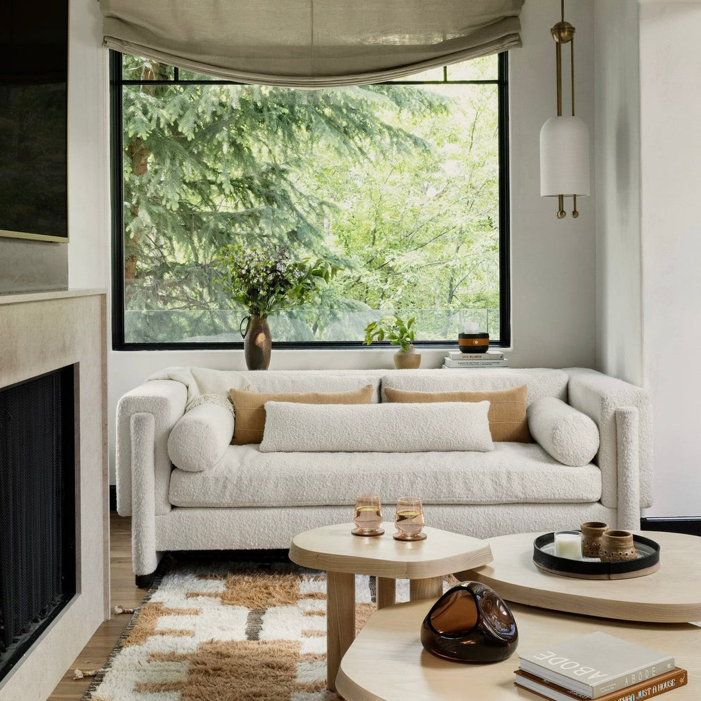 This Clérachic pendant on a pale wall by a large window onto trees, with a boucle sofa and low round tables below.