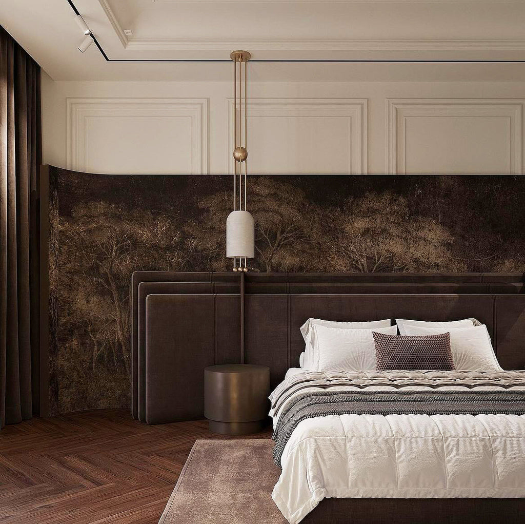A Clérachic pendant hung low beside a dark upholstered bed, in a room with white wall panelling and a forest-print mural.