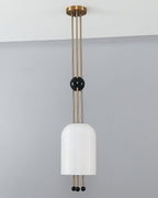 A Clérachic ribbed white pendant against a grey wall, with its brass canopy at the ceiling and a black ball on the rods.