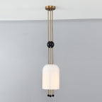 A Clérachic pendant lit against a grey wall, the ribbed white shade hung below a black ball on three brass rods.