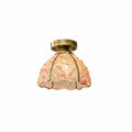 Pink and peach glass-chip shade lit from within, with a brass canopy, this Clérachic flush ceiling light on a white background.