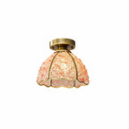 Pink and peach glass-chip shade lit from within, with a brass canopy, this Clérachic flush ceiling light on a white background.
