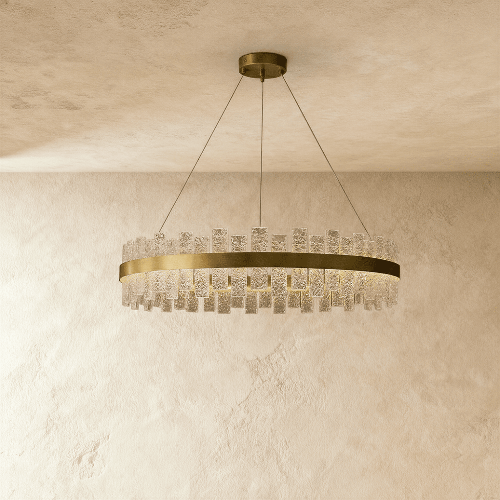 Clérachic round chandelier with a brushed brass ring and staggered textured glass panes, hung on slim cables from a ceiling plate.