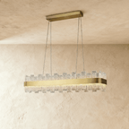 Clérachic linear chandelier with a brushed brass band and staggered textured glass panes, hanging on four cables from a bar canopy.