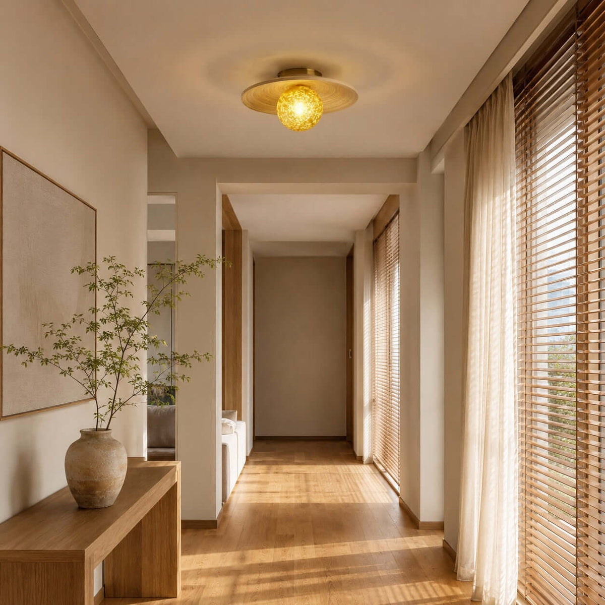 A yellow-globe Clérachic flush light with a bamboo disc hangs in a long hallway lined with wooden blinds and sheer curtains.