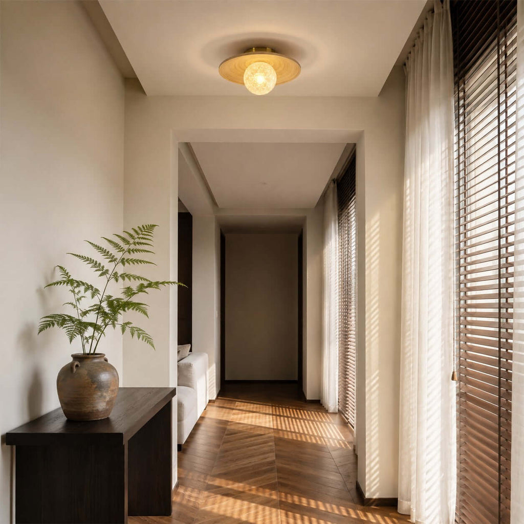 Lit from within, this Clérachic ceiling light with a bamboo disc hangs in a hallway with a dark console and herringbone floor.