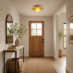 A small Clérachic flush light with a bamboo disc and warm globe hangs in a front hall with a timber door and a jute rug.