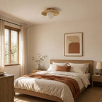 This Clérachic ceiling light with a frosted white globe hangs over a bedroom with a rust throw and linen bedding.
