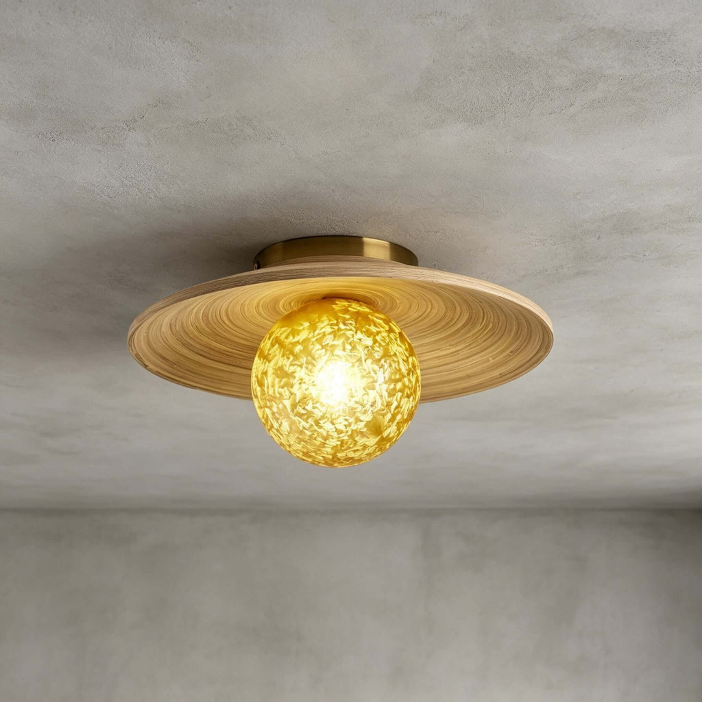 Close view of the spiral-grained bamboo disc and yellow ice-textured glass globe on this Clérachic ceiling light, on grey.