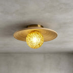 Close view of the spiral-grained bamboo disc and yellow ice-textured glass globe on this Clérachic ceiling light, on grey.