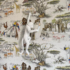 A white Clérachic monkey light stands out against a safari wallpaper of elephants, giraffes and parrots, its bulb held out.