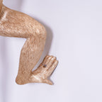 Close view of the gold monkey's bent leg and foot on this Clérachic wall light, showing the fine fur texture in the resin.