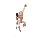 Gold monkey of this Clérachic wall light, one arm up, a white globe bulb in the other, on a plain white background.