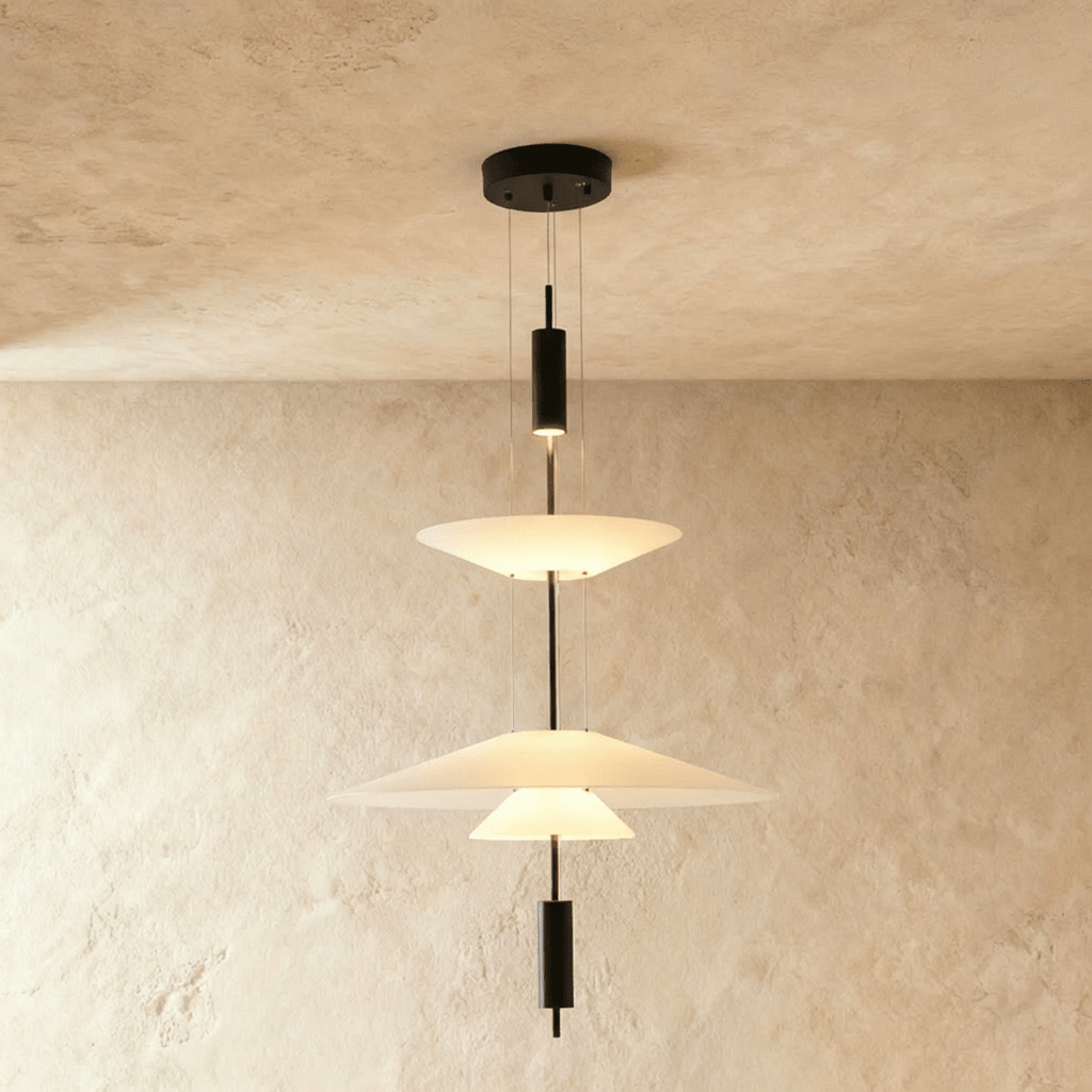 Clérachic tiered pendant light with three white frosted shades on a black rod, hung against a limewash wall.