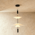 Clérachic tiered pendant light with three white frosted shades on a black rod, hung against a limewash wall.