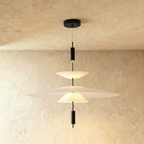 Clérachic layered pendant with a wide white frosted shade above a smaller cone, on black fittings, against limewash.