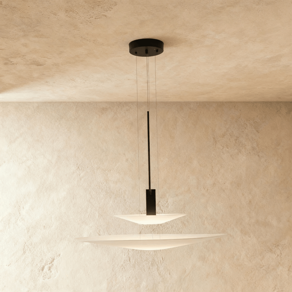 Clérachic two-tier pendant with a shallow white disc over a wider one on a black stem, against a limewash wall.