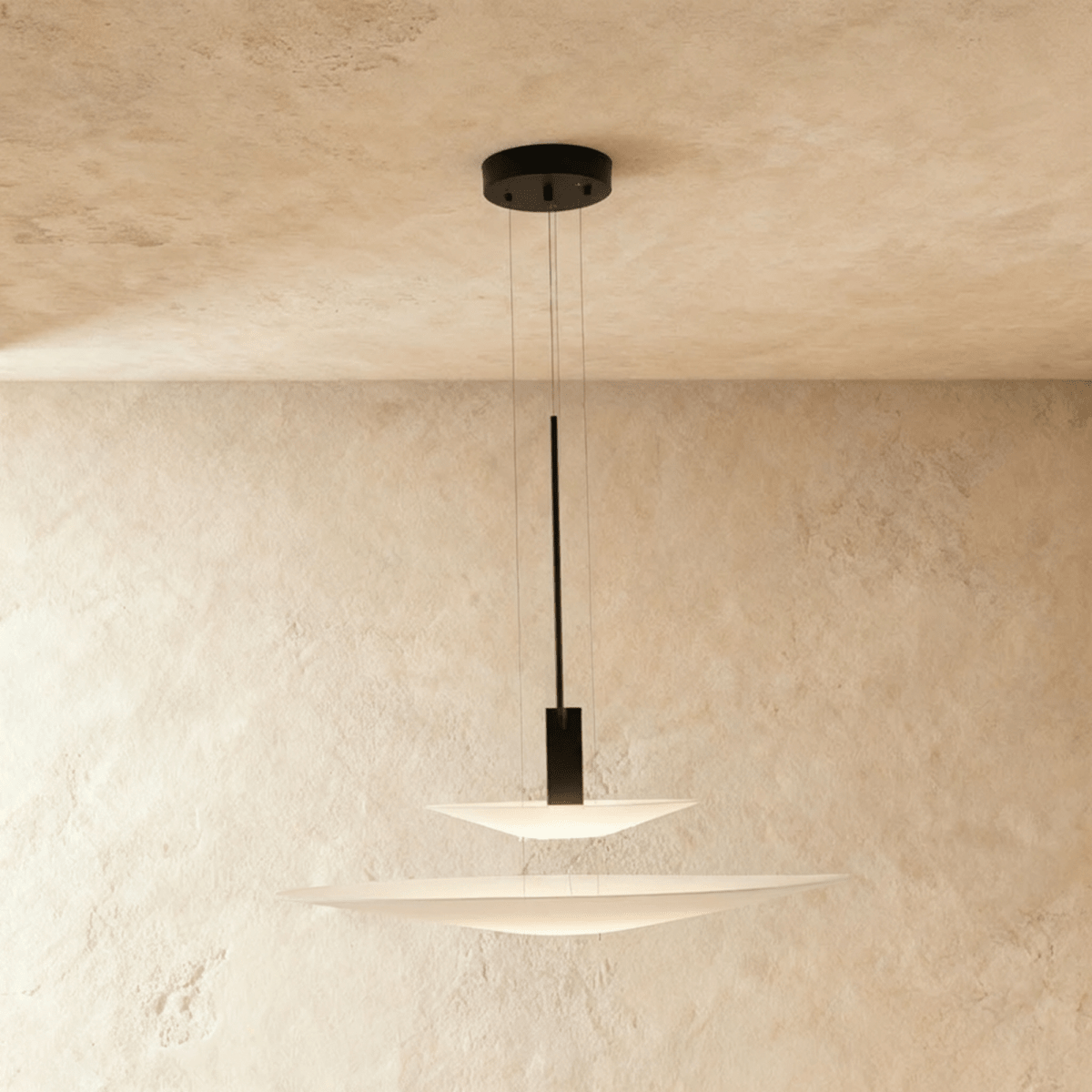 Clérachic two-tier pendant with a shallow white disc over a wider one on a black stem, against a limewash wall.